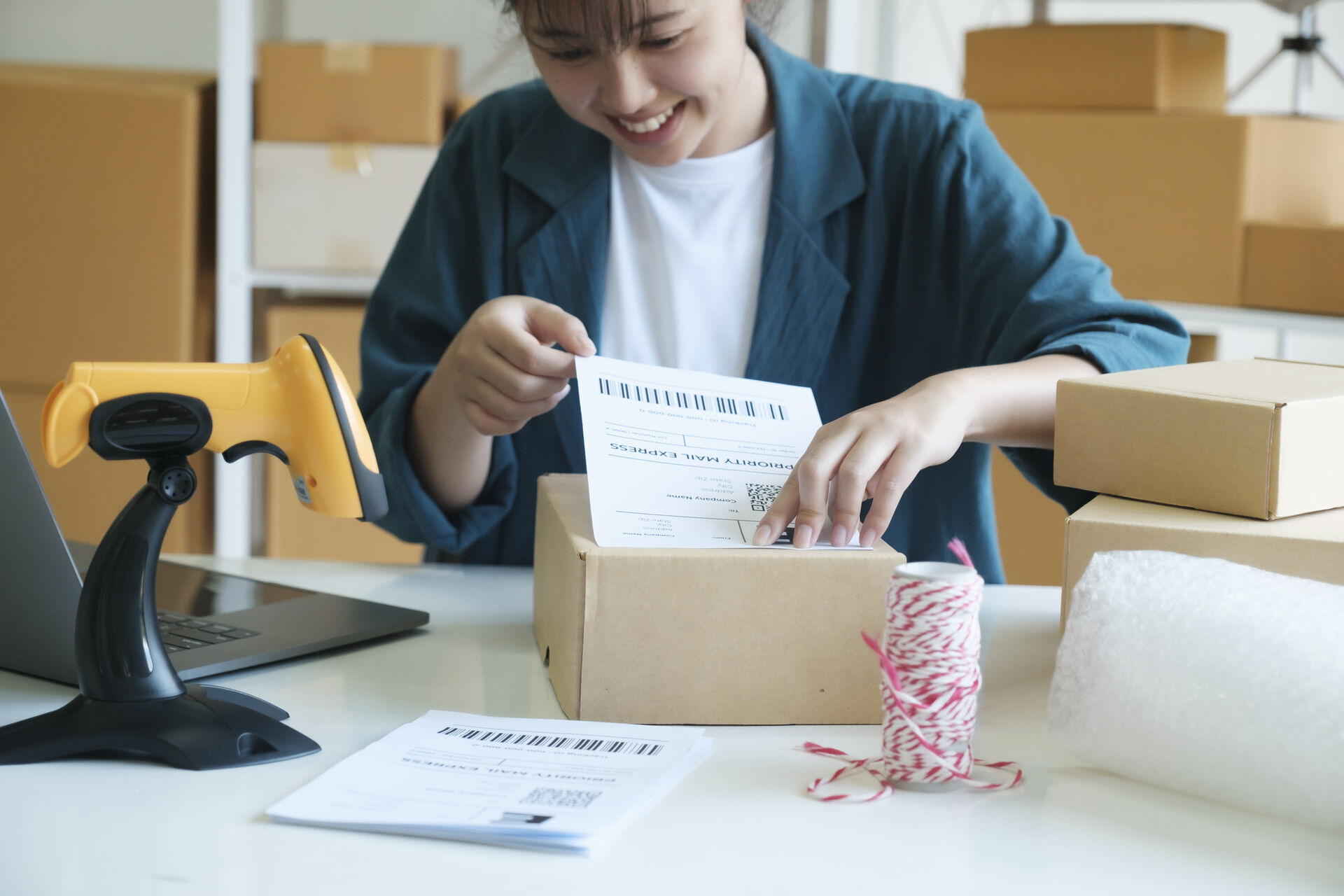 A young woman is attaching a shipping label to a package.